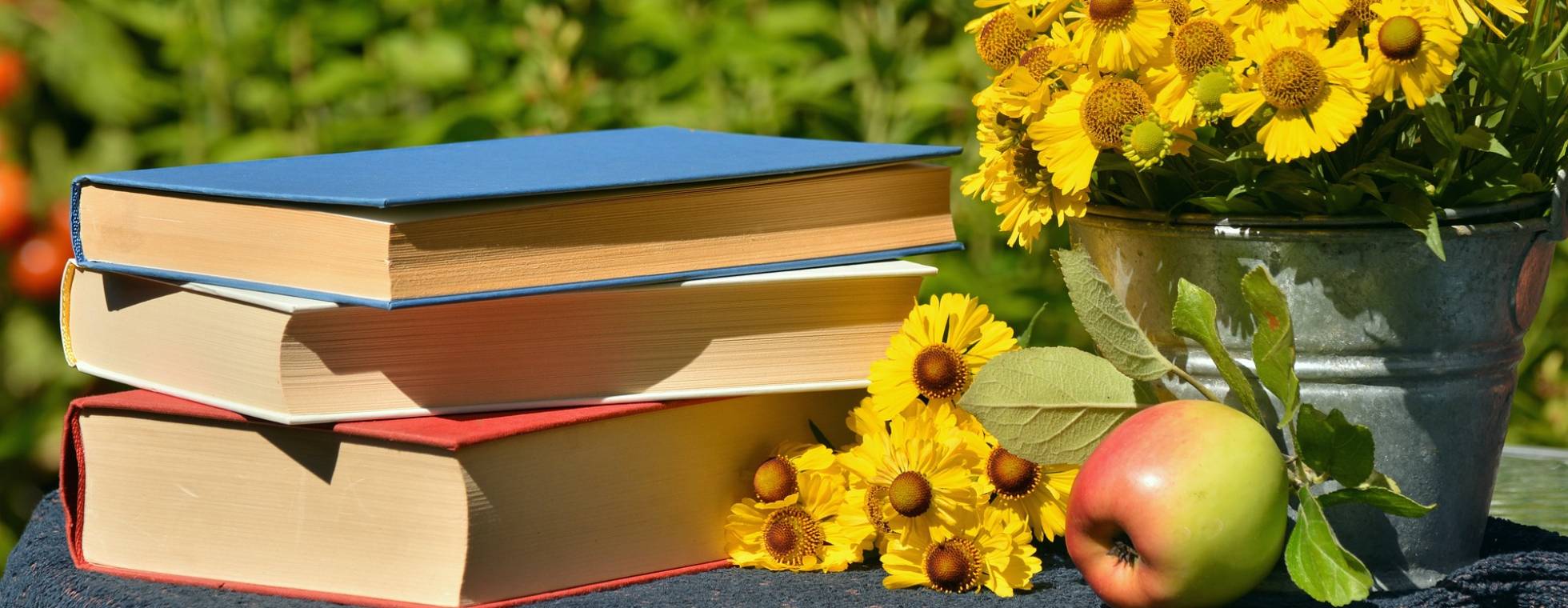 Blumen und Bücherstapel und ein Apfel