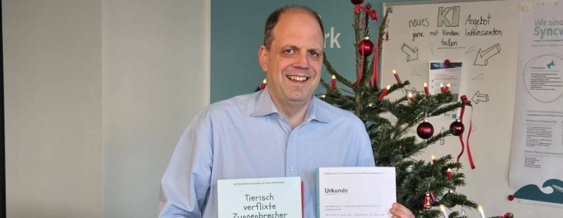 Martin Hartmann, Vorstandsmitglied von Sync-Work mit Kinderbuch und Patenschaftsurkunde